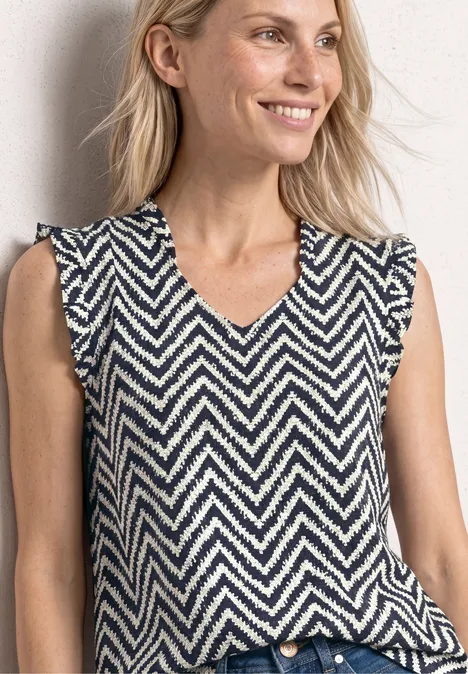 Eine ärmellose V-Neck-Strickweste mit dunklen und weißen Zickzackstreifen.