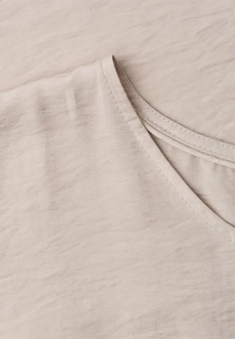 Close-up van een lichtbeige T-shirt met V-hals