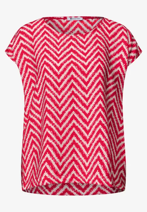 Locker sitzende Bluse mit rotem und weißem Zickzackmuster.