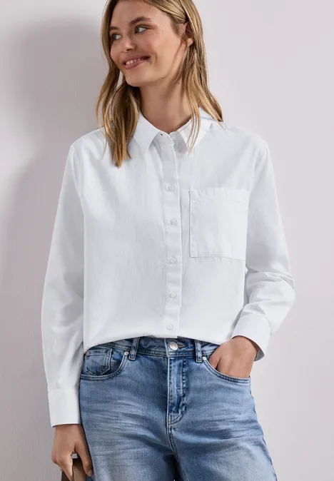 Blouse met lange mouwen en overhemdkraag in keperstof White Vrouw in wit overhemd en blauwe jeans tegen neutrale achtergrond.
