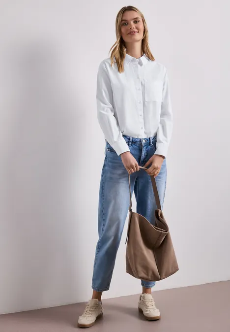 Blouse met lange mouwen en overhemdkraag in keperstof White Vrouw draagt witte blouse, wijde blauwe spijkerbroek, beige schoenen en houdt een bruine tas vast.