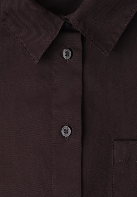 Dunkles Hemd mit Stehkragen und Knopfleiste; zwei Knöpfe und Brusttasche sichtbar.