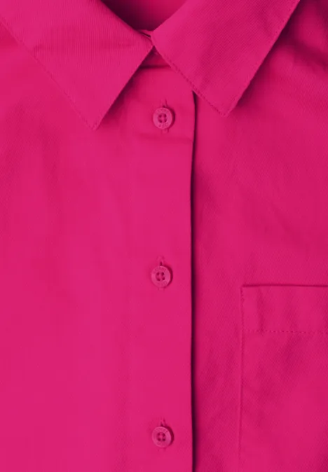 Nahaufnahme eines pinkfarbenen Hemdes mit Kragen, Knopfleiste und Brusttasche.
