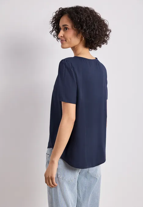 Blouse met ronde hals en korte pofmouwen shadowed navy Vrouw van achter gezien in een donkerblauw shirt met korte mouwen en lichte jeans