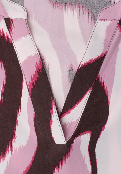 Gros plan sur un vêtement à encolure en V, motif abstrait rose, blanc et marron.
