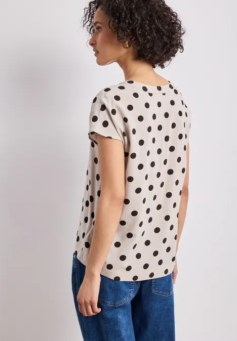 Femme vue de dos portant un t-shirt à pois et un jean
