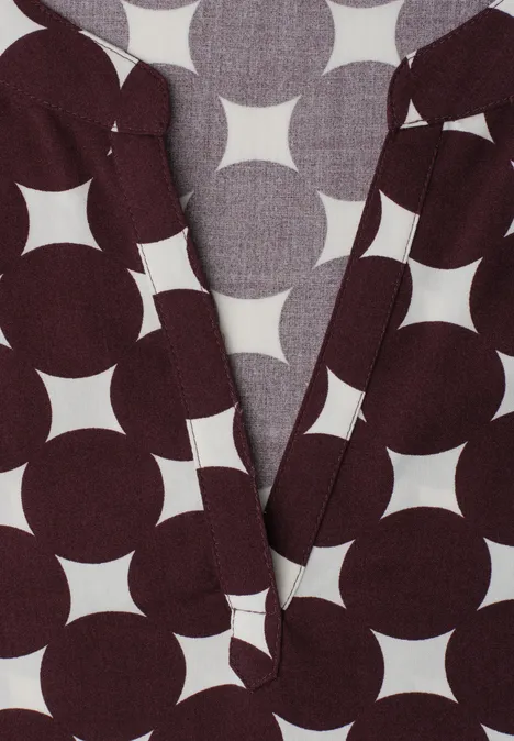 Vêtement sombre à motif géométrique blanc de cercles et étoiles, décolleté en V