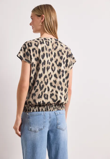 Frau von hinten in Jeans und kurzärmeligem Oberteil mit Leopardenmuster.