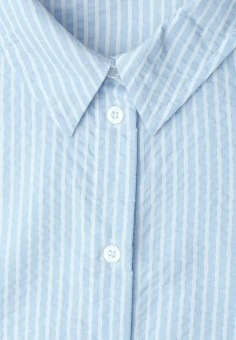 Lichtblauw overhemd met witte strepen, klassieke kraag en twee zichtbare knopen.