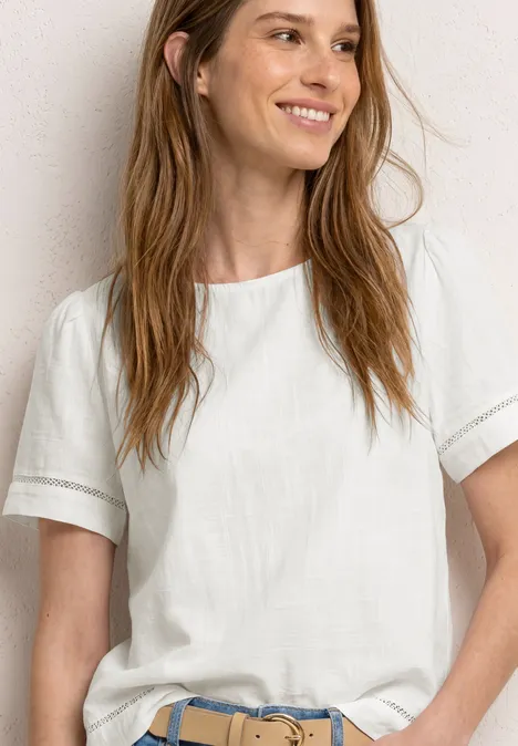 Persoon draagt eenvoudig wit T-shirt en spijkerbroek met blauwe riem voor neutrale achtergrond