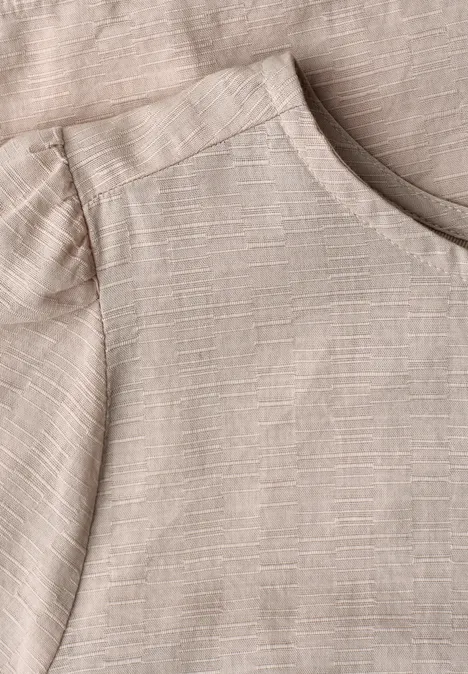 Close-up van een lichtbeige linnen T-shirt met ronde hals en gestructureerde stof.