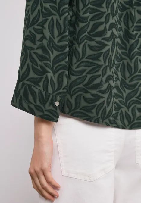 Close-up van een groen bladpatroon op een lange mouw blouse