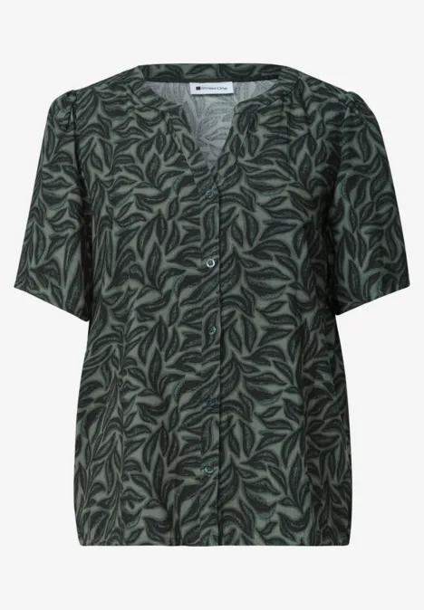 Donkergroene blouse met korte mouwen en lichtgroen bladpatroon.