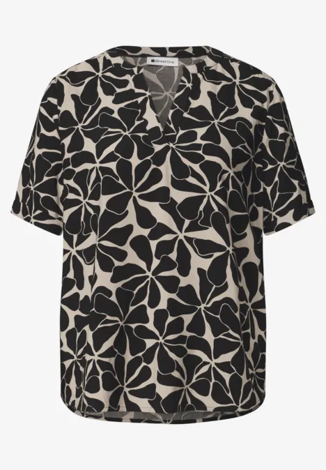 Schwarze Bluse mit beigem Blumenmuster, V-Ausschnitt und kurzen Ärmeln.