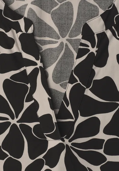 Nahaufnahme einer Bluse mit V-Ausschnitt und großem schwarz-weißem Blumenprint.