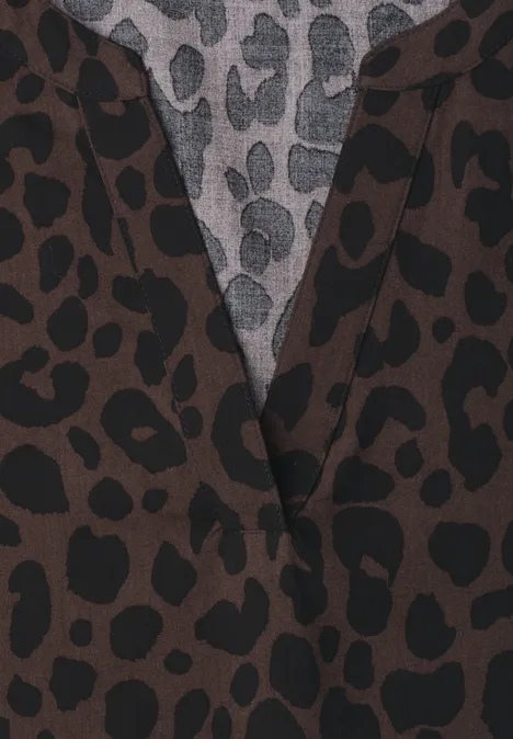 Nahaufnahme eines Kleidungsstücks mit braun-schwarzem Leopardenmuster und grauem Unterstoff mit schwarzen Flecken.
