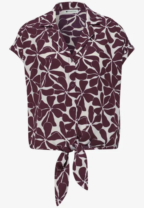 Kort mouwblouse met kraag, wit bladmotief op paarse achtergrond en knoop in de taille.