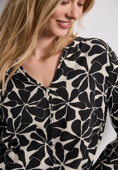 Vrouw draagt witte blouse met zwart bloemenprint en V-hals.
