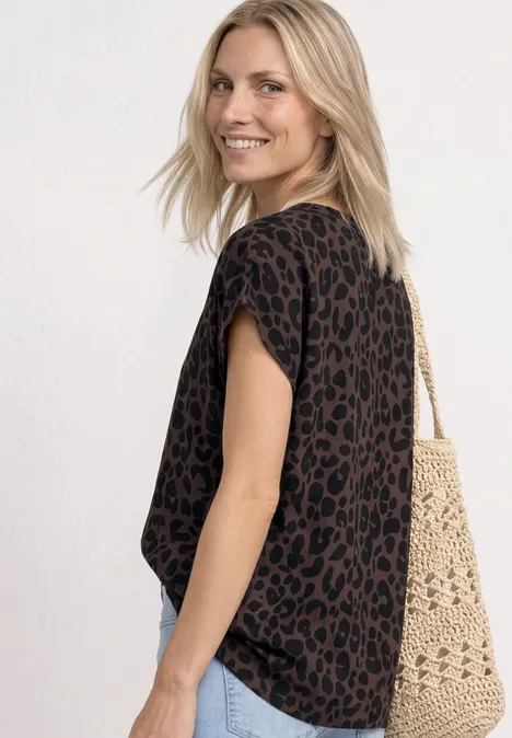 Vrouw draagt zwart shirt met luipaardprint en een gehaakte tas.