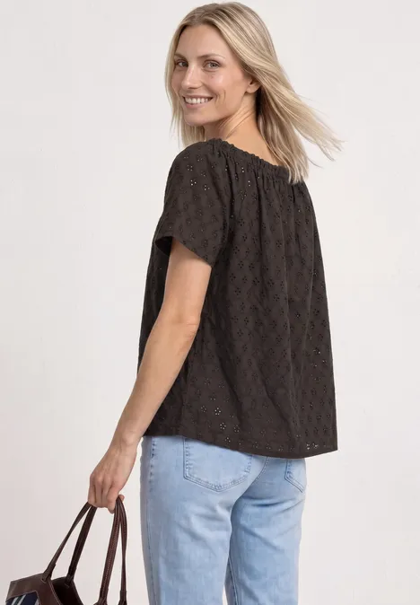 Carmen blouse espresso brown Frau in schwarzer Spitzenbluse und hellblauen Jeans, hält eine braune Tasche und blickt zur Seite.