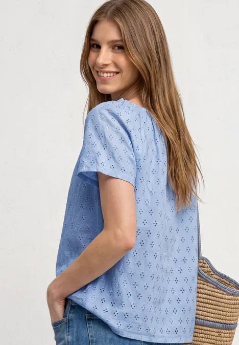 Carmen blouse cashmere blue Seitlich abgebildete Frau in hellblauer, kurzärmliger, bestickter Bluse mit Strohtasche in der Hand.