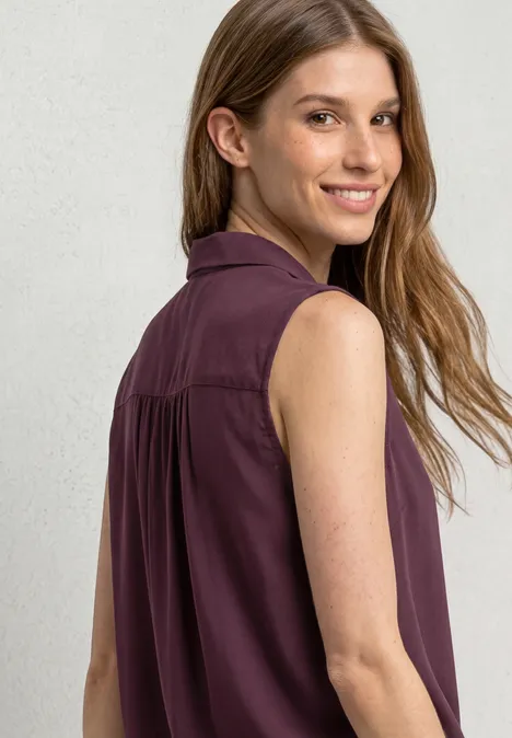 Blusentop mit Bowling-Kragen und Knoten rustic rouge Eine junge Frau mit langem Haar von hinten, trägt ein ärmelloses, dunkellila Oberteil.