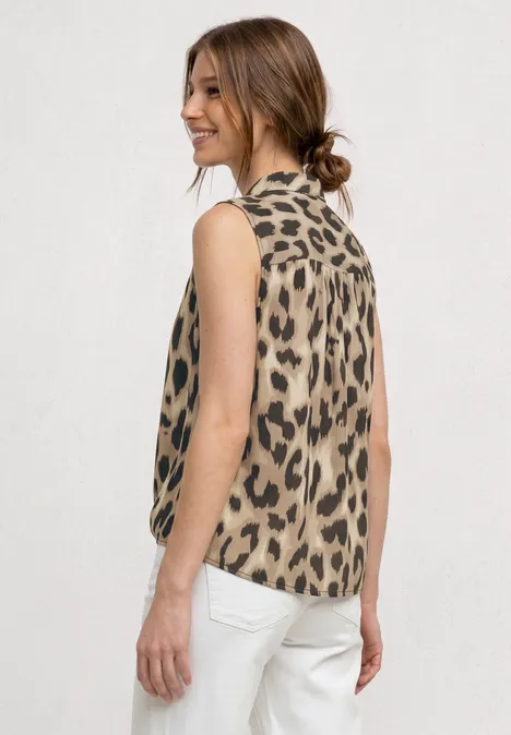 Frau von hinten, trägt ärmelloses Oberteil mit Leopardenmuster und weiße Hose, Haare zum Dutt gebunden.