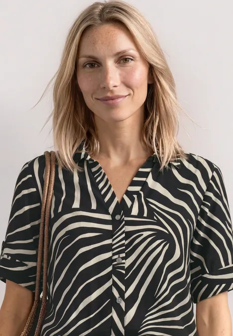 Chemisier à manches courtes avec détails à revers Black Femme avec un haut à motifs zèbre noir et blanc à manches courtes et un sac en bandoulière.