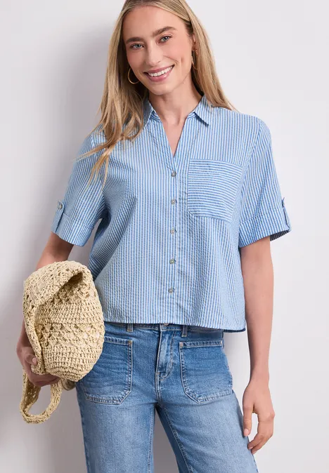 Kurzarm Hemdbluse mit Turn-Up-Details original blue Frau in blauem, kurzärmeligem Hemd und Jeans hält einen Strohhut in der Hand.