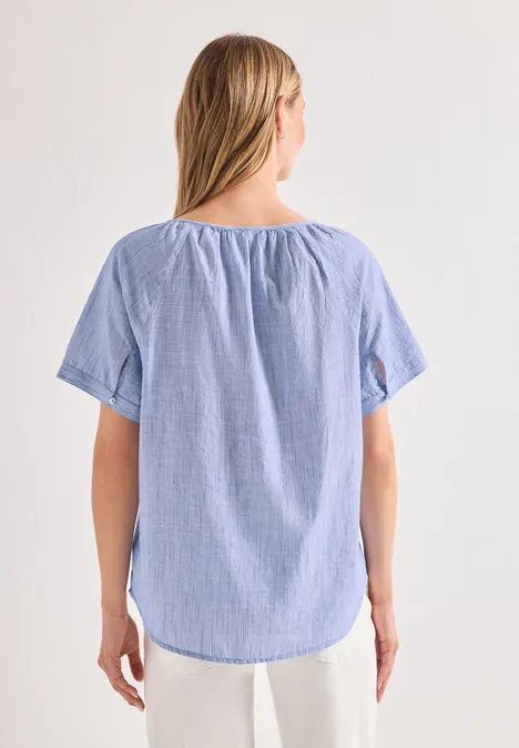 Frau von hinten in leichtem, blau-weiß gestreiftem Kurzarmshirt.