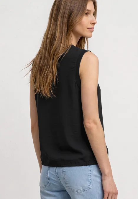 Rückenansicht einer Frau mit schwarzem Top ohne Ärmel und hellblauen Jeans.