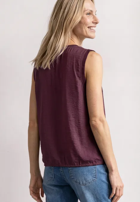 Blusentop mit Rundhals und Tape-Detail rustic rouge Frau von hinten in burgunderfarbenem ärmellosen Top und Jeans, blondes Haar locker gelassen.