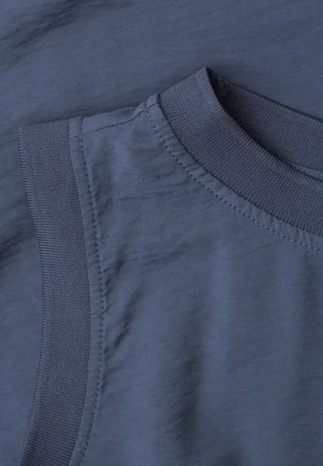 Nahaufnahme eines dunkelblauen T-Shirt-Ausschnitts mit sichtbaren Nähten und strukturiertem Stoff.