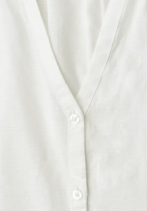 Close-up van een wit V-hals kledingstuk met knopen