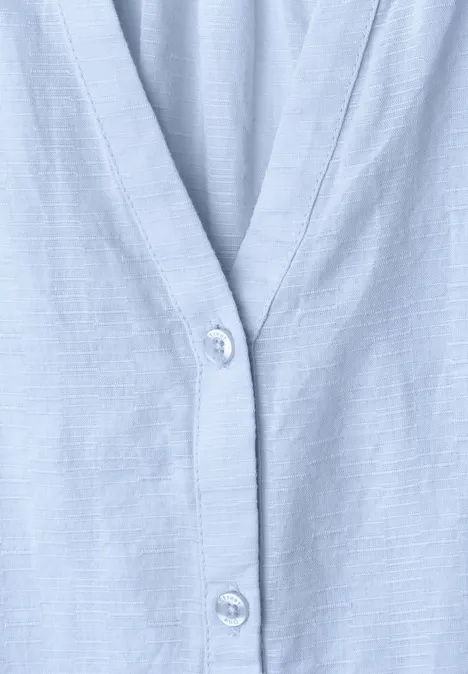Close-up van een lichtblauw overhemd met eenvoudige knoopsluiting.