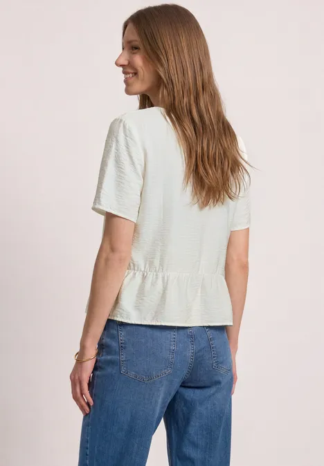 Kurzarm Bluse mit V-Neck und Schößchen off white Frau von hinten in weißem Kurzarmshirt mit Rüschenbund und blauen Jeans.