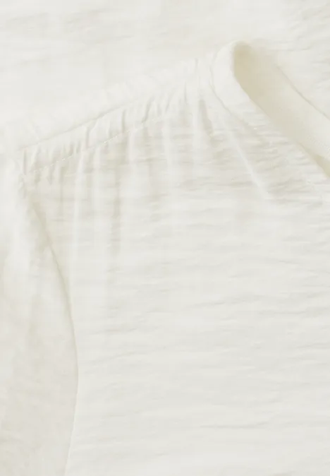 Kurzarm Bluse mit V-Neck und Schößchen off white Nahaufnahme eines weißen Baumwollshirts mit feiner Slubstruktur und dezenter Kräuselung an der Schulter