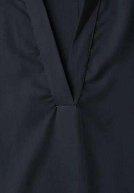 Detail van een donker kledingstuk met V-opening en siernaad.