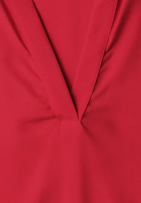 Roter Stoff mit V-förmigem Ausschnitt und feinen Falten.