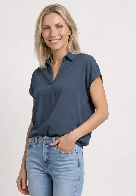 Blouseshirt met overhemdkraag en elastische zoom null Persoon in donkerblauw kort overhemd en lichte jeans, ontspannen staand voor een neutrale achtergrond.