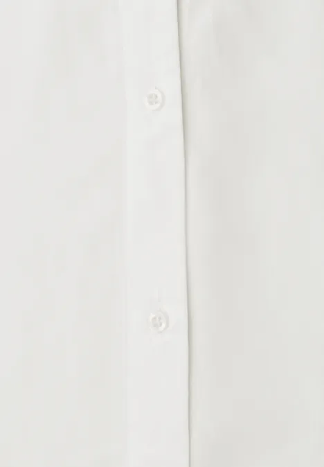 Blusentop mit Bowling-Kragen und Knoten off white Nahaufnahme eines weißen Hemdverschlusses mit Knopfleiste und weißen Knöpfen.