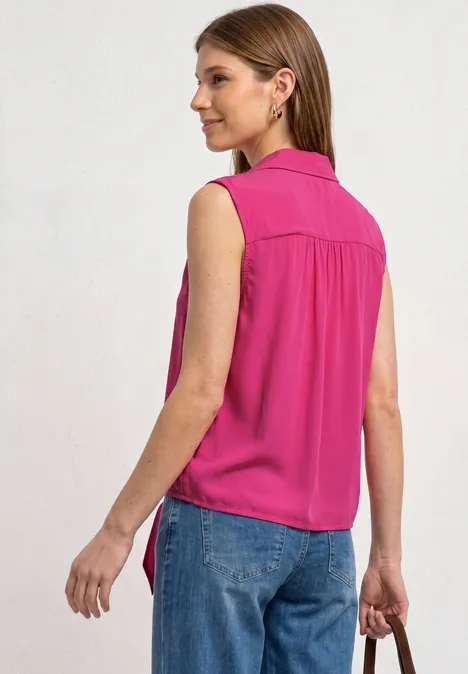 Blusentop mit Bowling-Kragen und Knoten magenta dream Frau von hinten in pinker ärmelloser Bluse und blauen Jeans, in der Hand eine kleine Clutch.