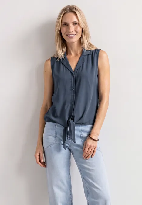 Blusentop mit Bowling-Kragen und Knoten ashen blue Eine blonde Frau lehnt vor weißer Wand, trägt ärmellose dunkle Bluse mit Knoten und helle Jeans.