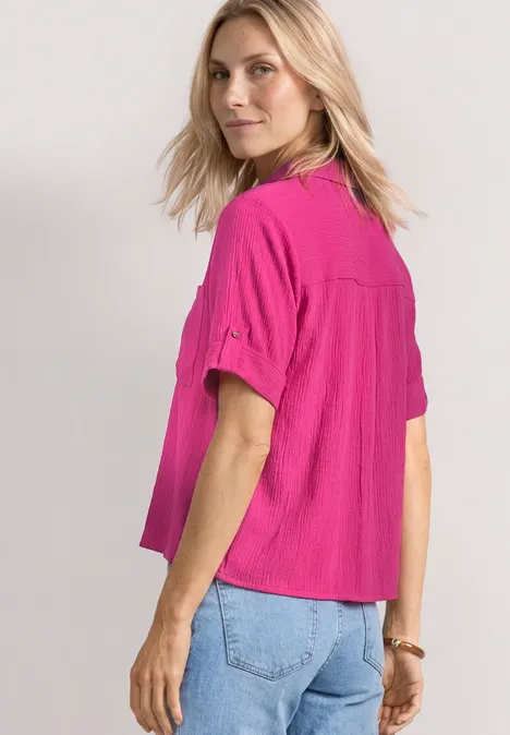 Overhemd met korte mouwen en omgeslagen manchetten magenta dream Blonde vrouw met felroze kort mouw shirt en spijkerbroek, half naar de camera gedraaid.