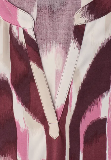 Close-up van een V-hals top in roze en paars met abstract dierenprint.