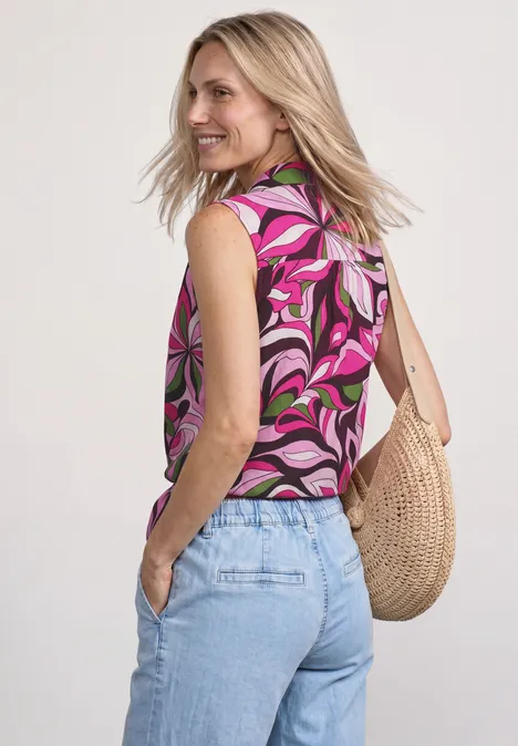 Blusentop mit Bowling-Kragen und Knoten magenta dream Frau von hinten mit pinkem, gemustertem Top, hellblauen Jeans und einer Strohtasche.