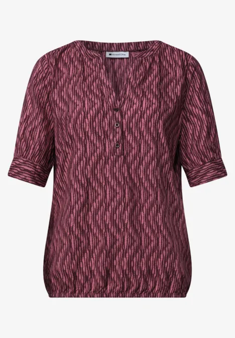 Blouse met korte mouwen, gespleten hals en elastische zoom blush berry Damesblouse met korte mouwen, V-hals en roze-zwart zigzagmotief.