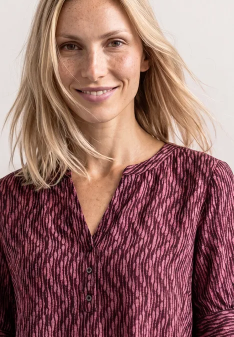 Blouse met korte mouwen, gespleten hals en elastische zoom blush berry Een persoon met lang blond haar draagt een rosé blouse met patroon en knoopsluiting.