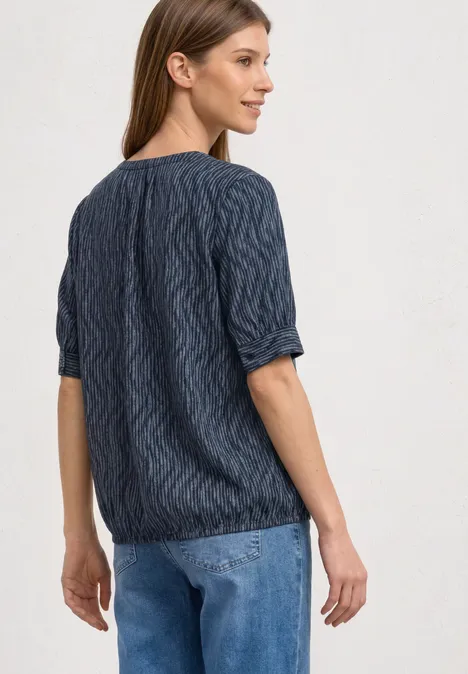Blouse met korte mouwen, gespleten hals en elastische zoom ashen blue Vrouw van achteren in een donkerblauwe kabeltrui met driekwartmouwen en een lichtblauwe spijkerbroek.