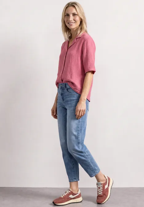Mousselineblouse met bowlingkraag blush berry Vrouw lachend in roze blouse en spijkerbroek staand